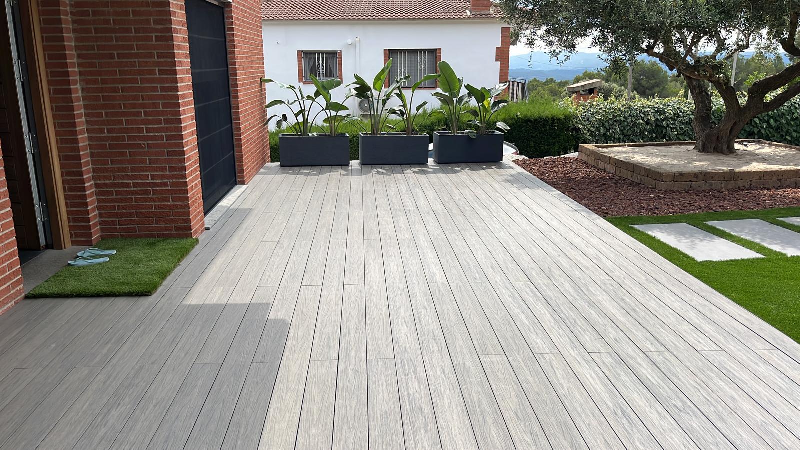 Terraza terminada con acabado de madera junto al césped Diseño de jardín con piscina y césped en Sitges Terraza terminada con acabado de madera junto al césped