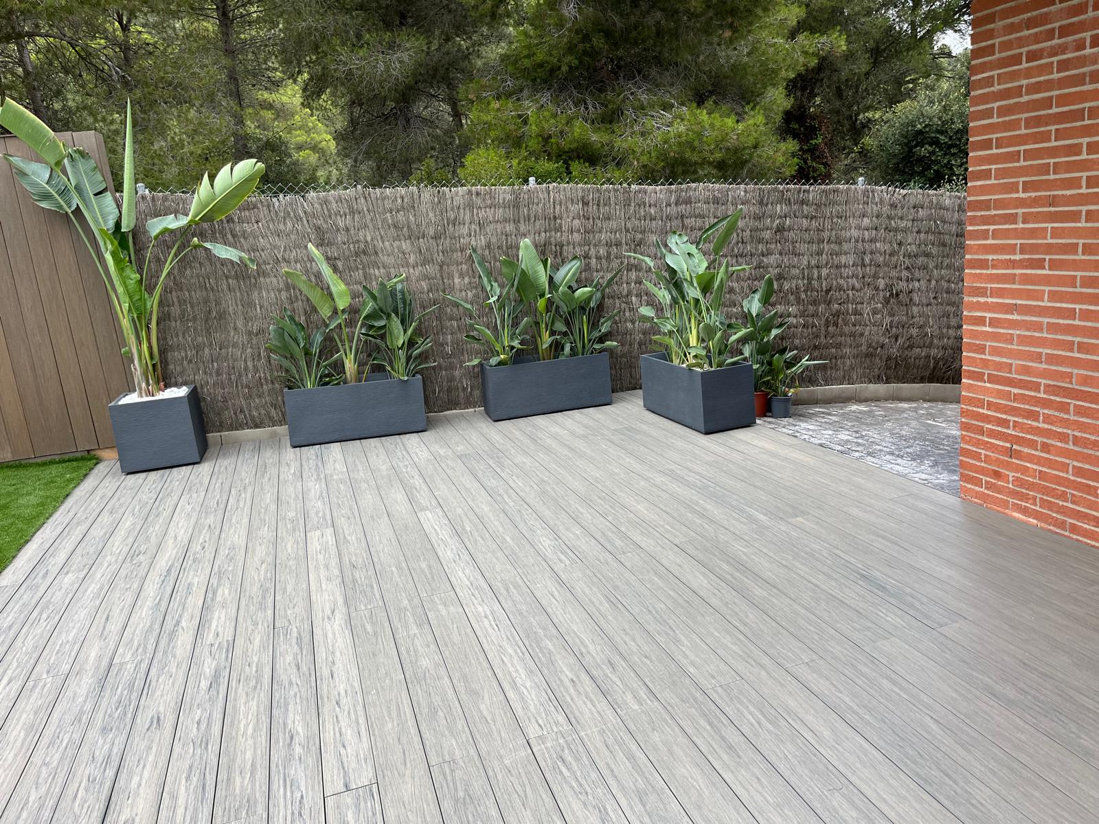 Jardineras sobre el pavimento gris de la terraza Diseño de jardín con piscina y césped en Sitges Jardineras sobre el pavimento gris de la terraza