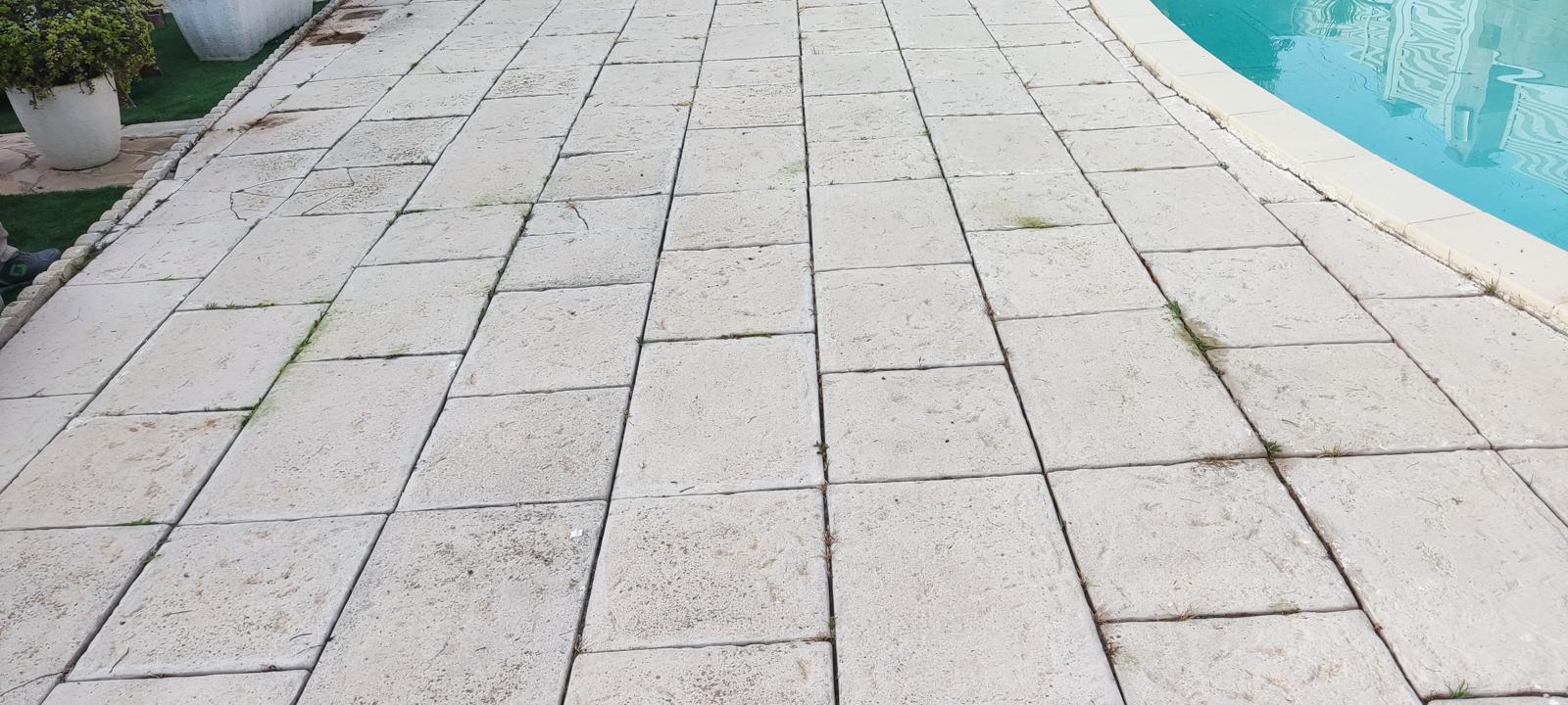 Pavimento de losas junto a la piscina antes de la renovación Jardín con piscina, tarima y pérgola en Castelldefels Pavimento de losas junto a la piscina antes de la renovación