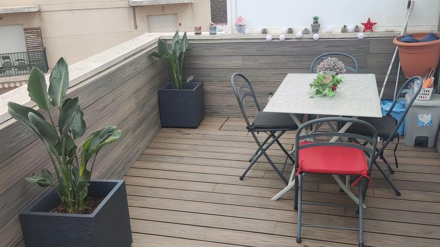 Terraza de piso en Cubelles con tarima de madera, revestimientos a juego, comedor y plantas